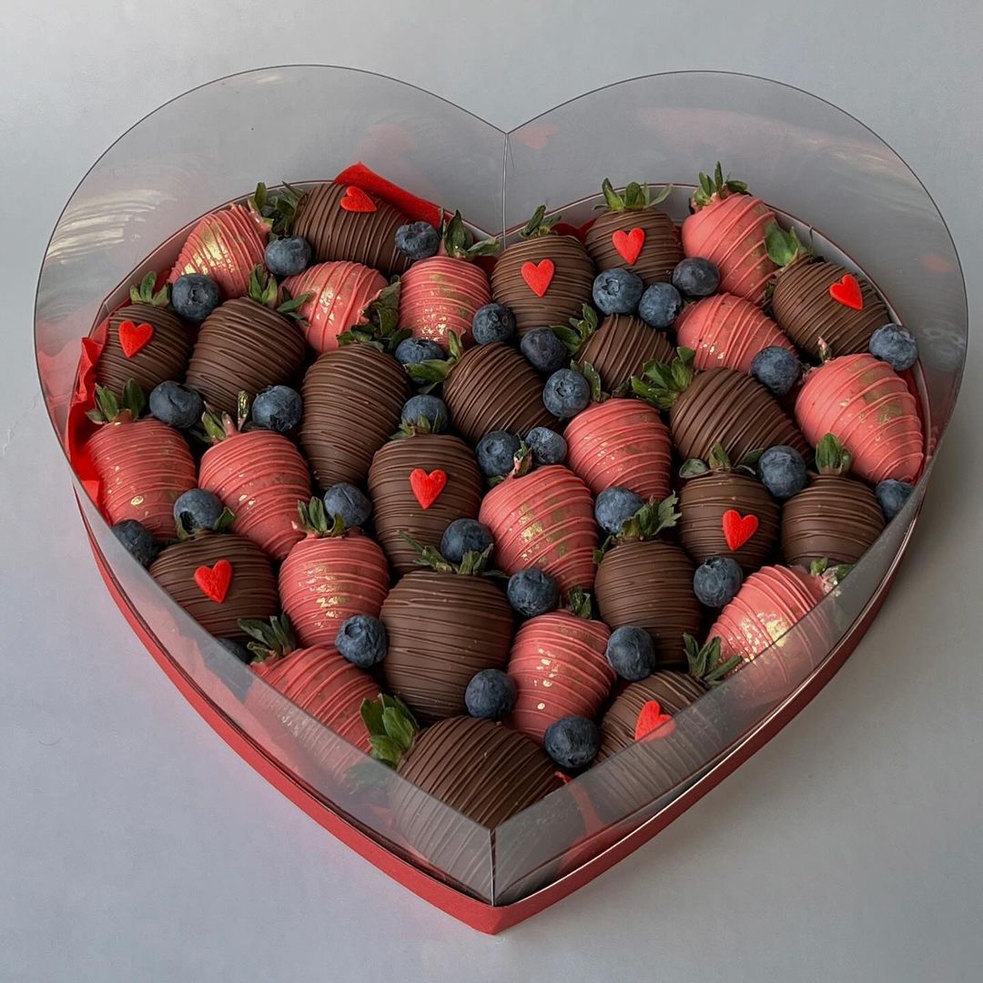 A heart-shaped box filled with chocolate-covered strawberries, a luxurious treat.