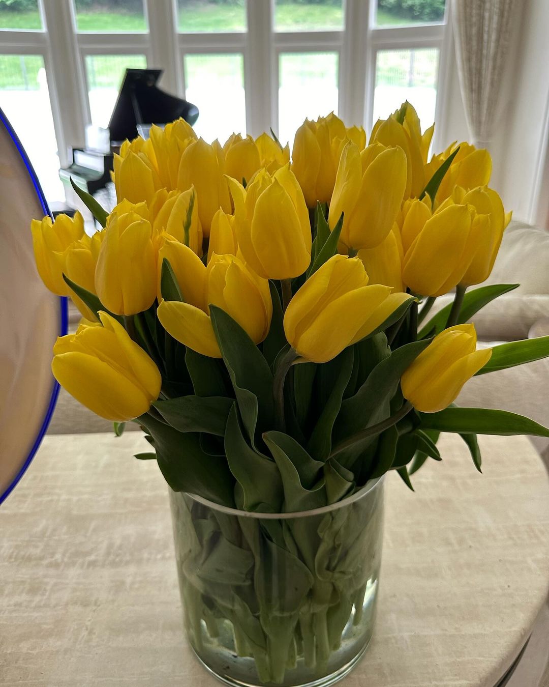 A vase filled with vibrant yellow tulips elegantly placed on a wooden table, showcasing their bright and cheerful appearance.
