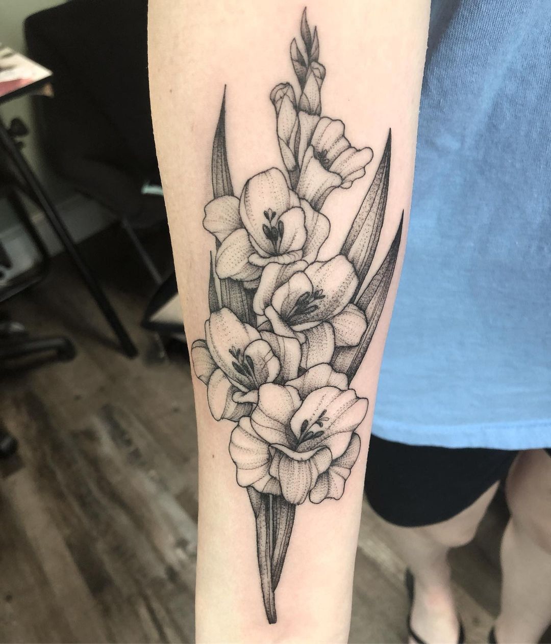 A gladiolus tattoo often symbolizes strength, honor, and remembrance, inspired by the flower